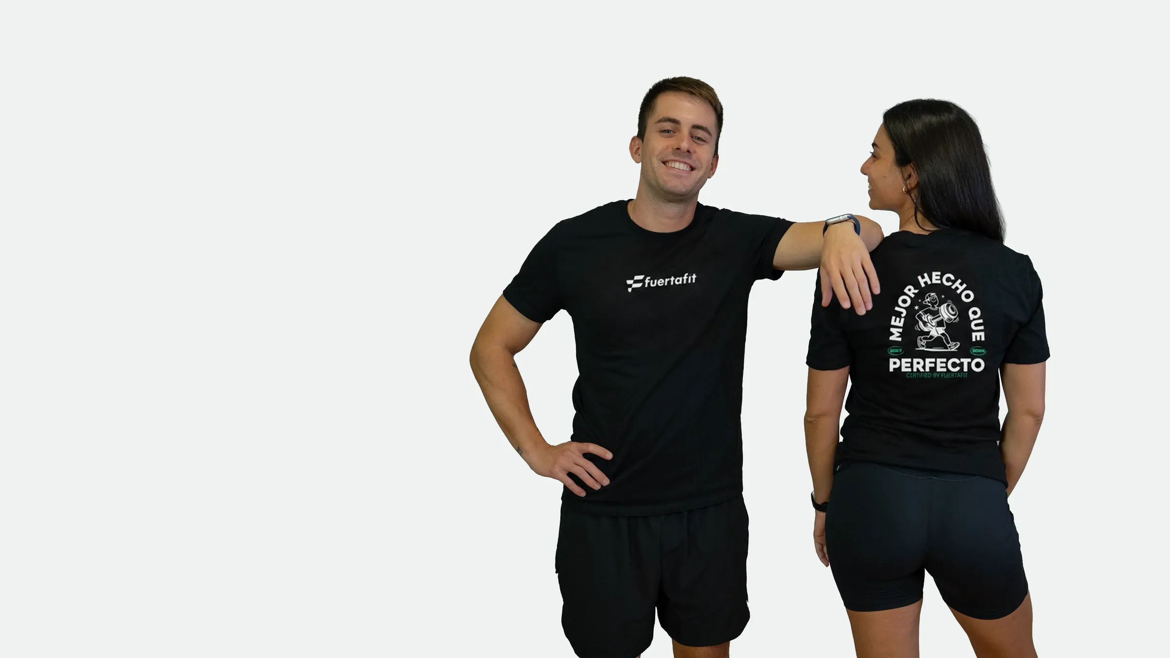 Dos entrenadores de Fuertafit con la camiseta negra Mejor hecho que perfecto ilustrada: él de frente y ella de espaldas
